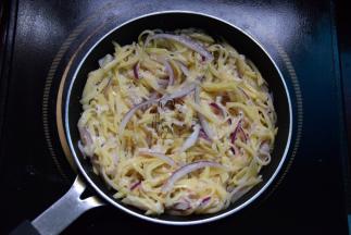 煎锅中倒入油，放入拌好的土豆丝，用筷子拨开成圆饼状，小火煎制