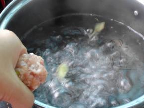 锅中倒入清水，放入姜片，大火烧开后，将手上涂一点水，将肉馅放入手掌心，握成拳，让肉馅从虎口挤出，形成丸子