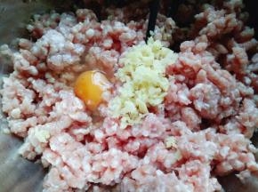 将切好的姜蒜加入肉糜中，再加入一只鸡蛋。