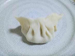 将饺子皮对折起来，捏紧，捏出皱褶。