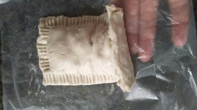 把做好的生胚抬起来一点，撕掉下面的塑料纸。拿起来放在铺了锡纸的烤盘里。