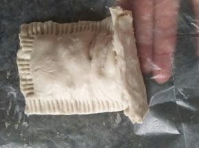 把做好的生胚抬起来一点，撕掉下面的塑料纸。拿起来放在铺了锡纸的烤盘里。