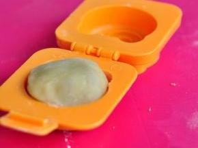 在熟糯米粉中滚一圈，塞入模具中，轻轻按平。