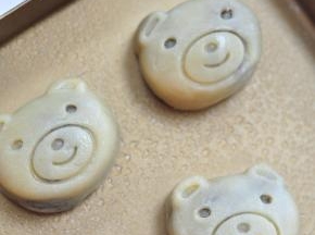 然后倒扣，小心把月饼磕出来，表面喷水。
 放进烤箱，上火190度，下火170度，先烤5分钟。