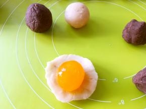 取一份馅，用手掌压扁，包裹上咸蛋黄，收好收口