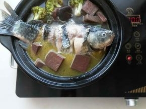 电陶炉大火转小火熬煮，用筷子将适量血块放在鱼身下面，防止鱼粘锅，