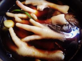 锅里的酱汁微微冒泡的时候加入鸡脚，盖上盖子。