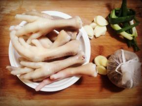 先将鸡脚洗干净，然后用100度左右的开水泡一下，沥干水分，然后准备好姜片，蒜片，葱段。（如果想卤包的香味更特出，可以提前讲卤包放入锅中慢火煮15-30分钟）