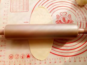 取一份面团，用阳晨金色不粘擀面杖擀成牛舌形。