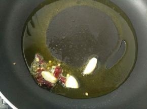 油温五成热时，倒入蒜瓣和干辣椒，炒个三十秒