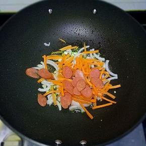 依次放入洋葱丝、胡萝卜丝、香肠，翻炒至软