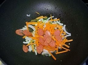 依次放入洋葱丝、胡萝卜丝、香肠，翻炒至软