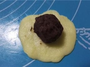 取一白色面团，放上豆沙馅