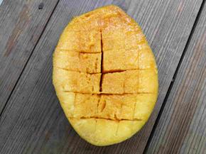 芒果沿果核切成三部分，果核弃之，两瓣果肉用刀尖切出方网格状，注意不要切透皮