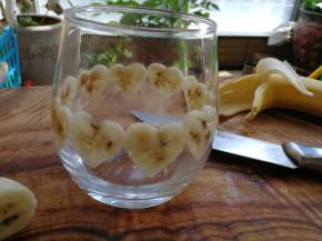 取一个玻璃杯，洗净后擦干杯内水份，将印好的香蕉薄片贴一圈在玻璃杯内壁上