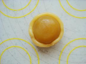 饼皮按扁放入馅料，同样方法用虎口慢慢上推捏紧收口包好。