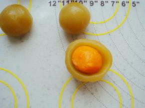 莲蓉馅在手心里按扁，包入一颗咸蛋黄。