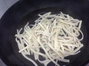锅里水煮开，加入1小勺盐进去搅拌匀，将千张丝加入热水中烫1、2分钟，捞出沥水备用