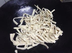 锅内底油，沥干的千张丝倒入翻炒