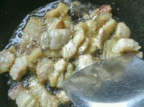 锅里烧水，把整块五花肉入锅煮一下 ，再捞起切片，然后放入炒锅中煸炒