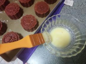 定型过程中来制作蛋黄液，取蛋黄一个，加一点点水，调成蛋黄液。月饼定型好以后拿出来，用羊毛刷子，粘取少量蛋黄液，然后刷子在碗边蹭一下，蹭掉多余的蛋液，轻轻刷在月饼上。