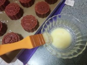 定型过程中来制作蛋黄液，取蛋黄一个，加一点点水，调成蛋黄液。月饼定型好以后拿出来，用羊毛刷子，粘取少量蛋黄液，然后刷子在碗边蹭一下，蹭掉多余的蛋液，轻轻刷在月饼上。