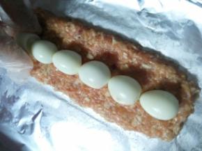 烤盘上铺一张锡纸，把搅拌好的肉泥分一半铺在上面压平，再把鹌鹑蛋摆在上面