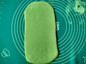 面团排气分成两份，另一份先盖上保鲜膜防风干。将面团擀成长方形面片。