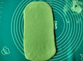 面团排气分成两份，另一份先盖上保鲜膜防风干。将面团擀成长方形面片。