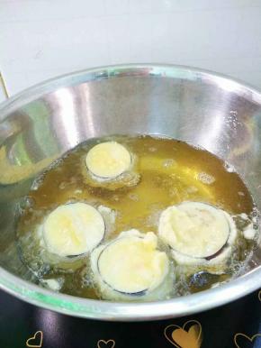 锅里适量植物油烧五成热，用筷子将茄子逐个放入油锅里，以小火慢慢炸。