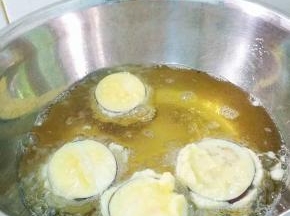 锅里适量植物油烧五成热，用筷子将茄子逐个放入油锅里，以小火慢慢炸。