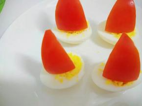 西红柿用牙签固定插在鸡蛋上，摆入菜盘。