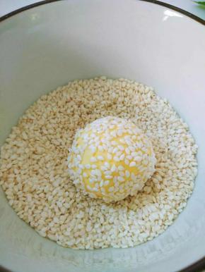 粘上白芝麻，双手再稍微用力将芝麻牢牢的粘在圆球上，制成麻团。