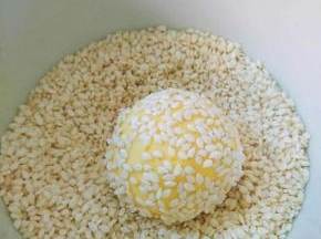粘上白芝麻，双手再稍微用力将芝麻牢牢的粘在圆球上，制成麻团。