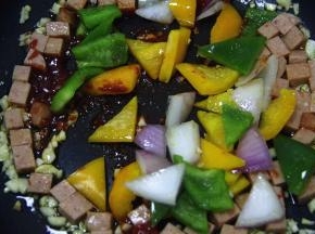 直至茄酱炒至粘稠后，加彩椒丁、洋葱丁并加入适量的糖、盐