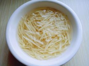 土豆去皮，用插板插土豆丝。之后放在大口器具中，用冷水冲洗两遍，再换清水泡5分钟，捞出淋干水份。