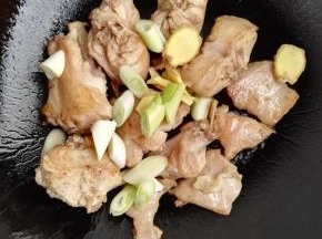 5、煸至兔肉出现黄色的焦边时，将姜片和葱段加入，炒出葱姜的香味。