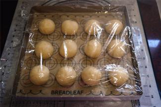 取出面团进行排气、揉圆，盖上保鲜膜醒发15分钟左右。然后分成12份，揉圆，排放入烤盘，放入烤箱进行最后发酵，时间约1小时。