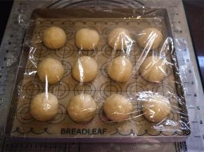 取出面团进行排气、揉圆，盖上保鲜膜醒发15分钟左右。然后分成12份，揉圆，排放入烤盘，放入烤箱进行最后发酵，时间约1小时。