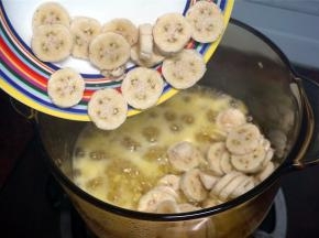 将玻璃锅转移到炉灶上，中火煮沸腾，至糖完全融化，然后加入粉蕉片一起熬煮。