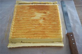 待蛋糕体降至温温的状态时翻转过来，将首尾斜斜切去1厘米宽，然后每隔2厘米用刀划一条浅痕。