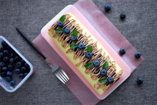 表面装饰：蛋糕卷表面先抹上一层蓝莓果酱，然后用巧克力奶油拉线装饰，最后放上蓝莓，摆上薄荷叶，完成。