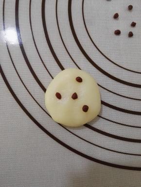 13、取出一个白色的冰皮用手掌按一下，取几个小可可冰皮随意的按在上面。