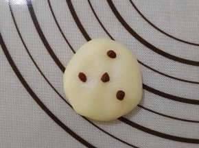 13、取出一个白色的冰皮用手掌按一下，取几个小可可冰皮随意的按在上面。