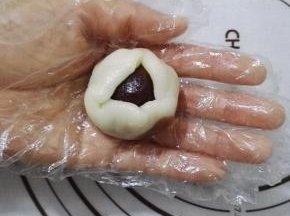 15、将冰皮翻过来包上红豆馅，用虎口慢慢收口。