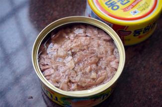 然后倒入整盒金枪鱼罐头，加入适量的酱油，快速翻炒。