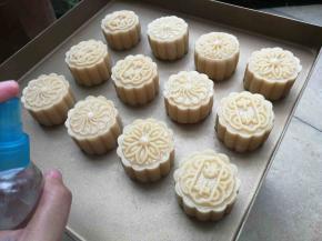 压模直接垂直在烤盘上，用手轻轻压出月饼花纹，依次压好12个月饼坯，然后用喷雾壶在月饼上喷洒一点水雾，保持月饼饼皮湿度，以免进炉烘烤开裂