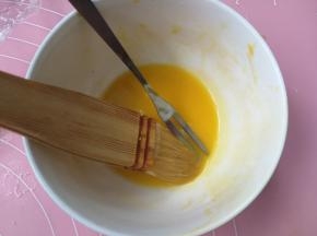 烤8分钟后，取出烤盘，在月饼上刷一层薄薄的蛋黄液，一定要把毛刷上粘的蛋黄液在碗边多滤几遍，然后再刷月饼，薄薄的一层就可以，否则月饼花纹就不清晰啦