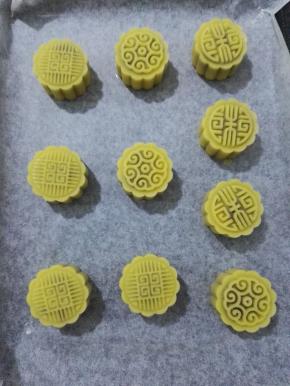 14、用月饼模具压出花形，烤箱预热上火190度，下火170度，预热完成，用喷壶在月饼上喷点水后放入烤箱，烤10分钟至月饼的表面微微上色。