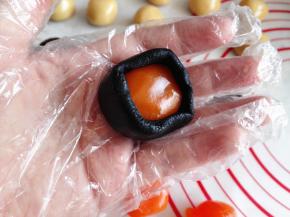 7.	取一个黑芝麻团，用手按扁，中间放一个蛋黄，再将蛋黄包住，